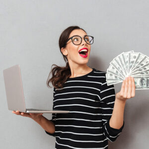 femme heureuse avec de l'argent et un ordinateur portable dans les mains