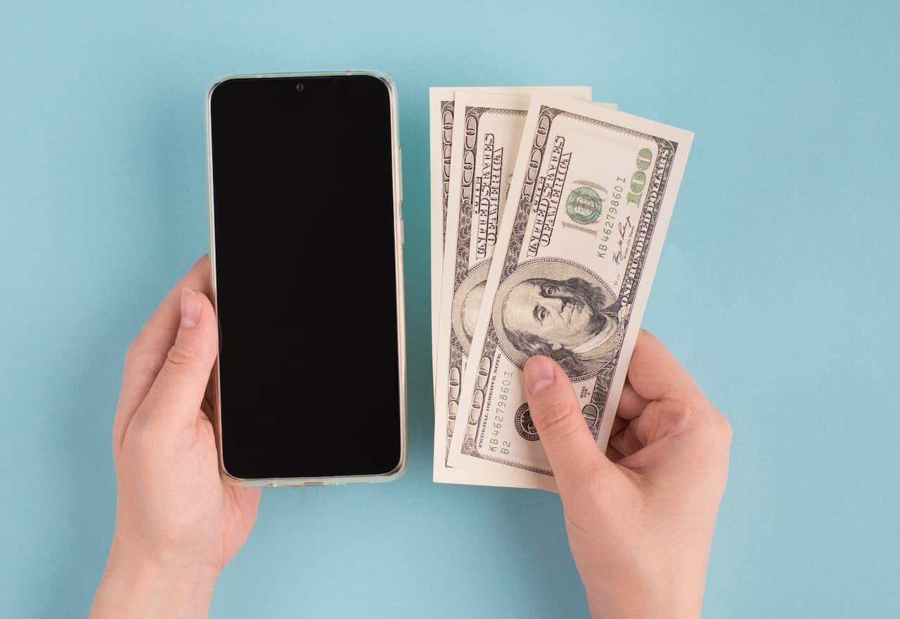 Thumbnail-For-Hands holding small amount of cash and a smartphone-By-Credit Instant (1)
